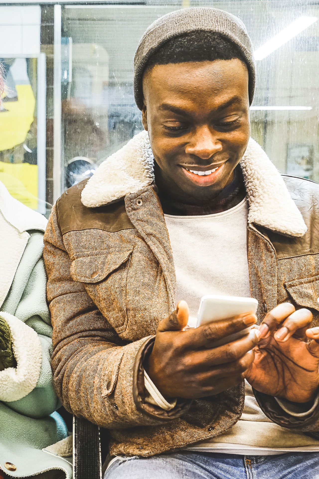 A young man uses his smartphone on public transport and smiles