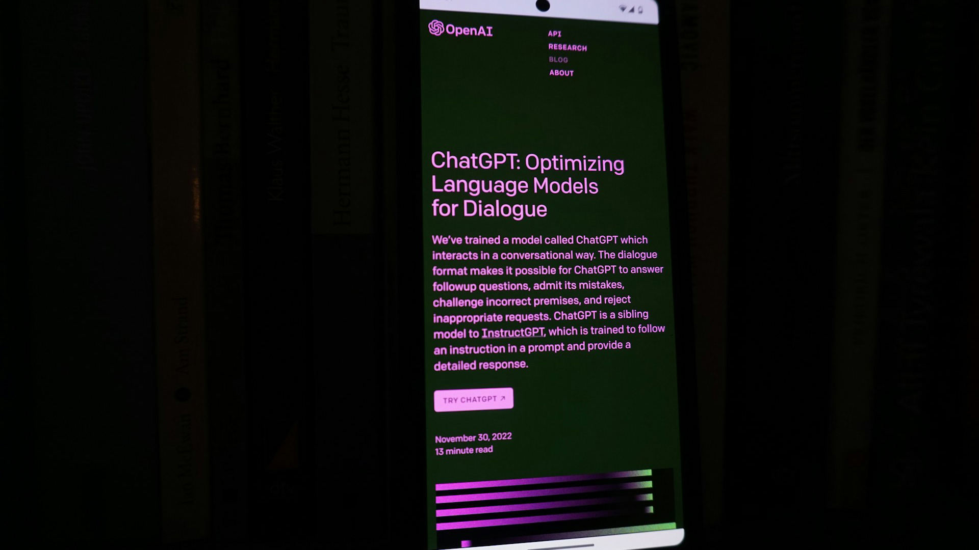 Capture d'écran d'un smartphone affichant une page dédiée à ChatGPT d'OpenAI, intitulée 'ChatGPT: Optimizing Language Models for Dialogue', avec des détails sur les capacités et objectifs du modèle, en environnement sombre.